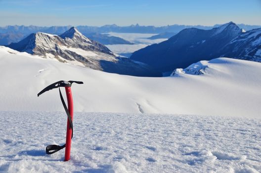 Ice ax stuck in the snow high in the mountains above the glacier