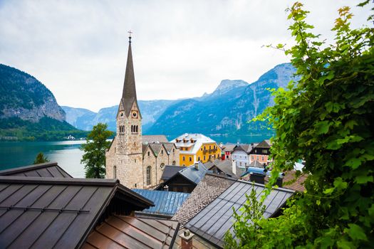 Hallstatt, Austria - August 7, 2013: View of Hallstatt village with Christuskirche church bell tower on lake shore and Alps behind, Austria