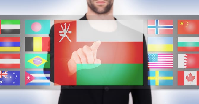 Hand pushing on a touch screen interface, choosing language or country, Oman