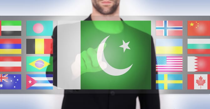 Hand pushing on a touch screen interface, choosing language or country, Pakistan