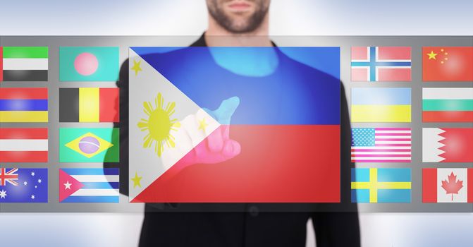 Hand pushing on a touch screen interface, choosing language or country, the Philippines