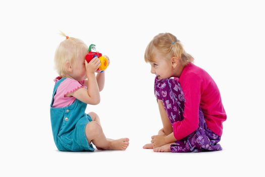 sisters taking pictures of each other with toy camera - isolated on white