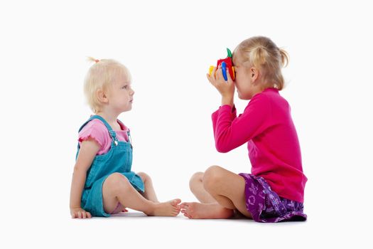 sisters taking pictures of each other with toy camera - isolated on white