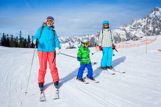 Ski, winter, snow, skiers, sun and fun - Mother with two happy kids enjoying winter vacations.