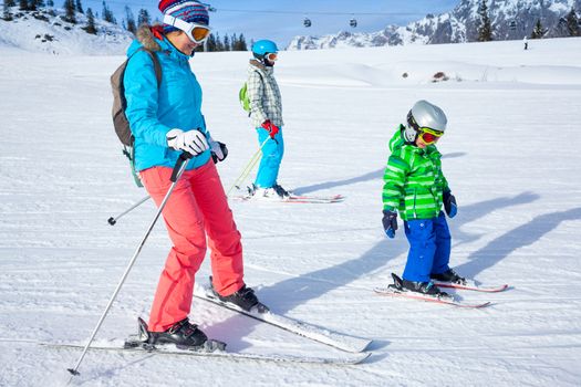 Ski, winter, snow, skiers, sun and fun - Mother with two happy kids enjoying winter vacations.