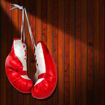 Pair of red and white boxing gloves hanging on wooden wall with shadows