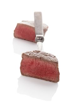 Delicious rare steak mignon on fork isolated on white background. Culinary beefsteak eating.