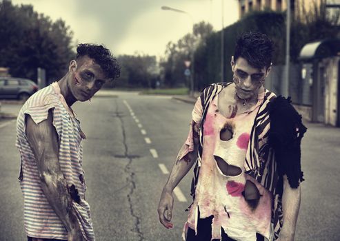 Two male zombies standing in empty city street looking at camera