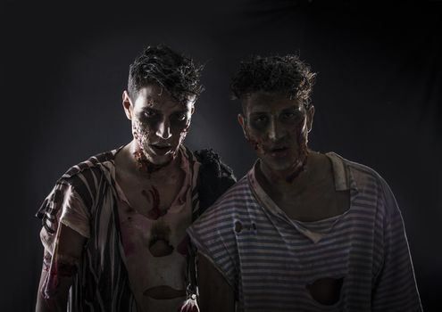 Two male zombies standing on black smoky background, head and shoulder shot. Halloween theme