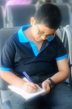 Young boy taking notes and writing on a pad