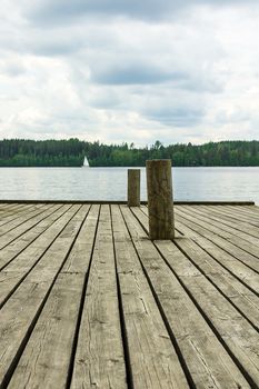 Docking poles on the old wooden pier with a lake and forest background