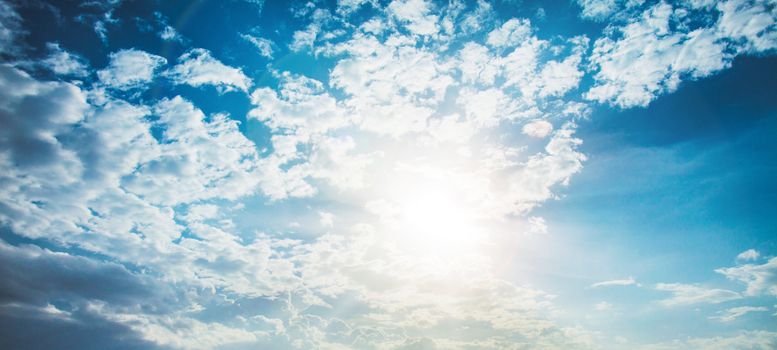 shining sun with lens flare. Blue sky with clouds background