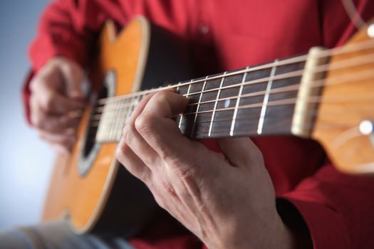 closeup of hands of a musician playing acoustic guitar