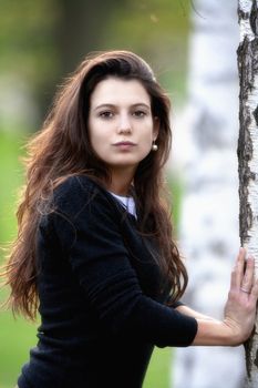 portrait of a beautiful brunette standing in birch forest