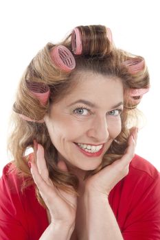 happy middle-aged woman in red with hair rollers - isolated on white