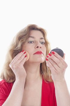 middle-aged woman in red putting on makeup - isolated on white