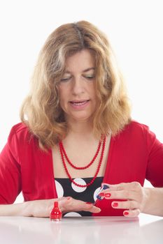 middle-aged woman in red painting her nails - isolated on white