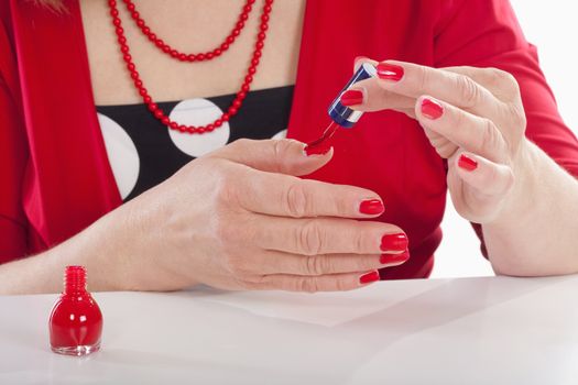 closeup of a middle-aged woman in red painting her nails