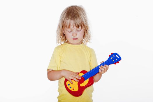 boy with long blond hair playing with toy guitar - isolated on white