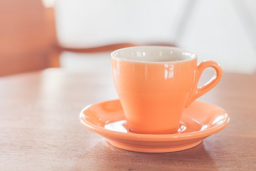 Orange coffee cup on wooden table, stock photo