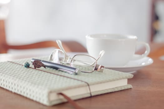 Notebook with pen, eyeglasses and white coffee cup, stock photo
