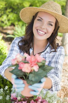 Attractive Happy Young Adult Woman Wearing Hat and Gloves Gardening Outdoors.