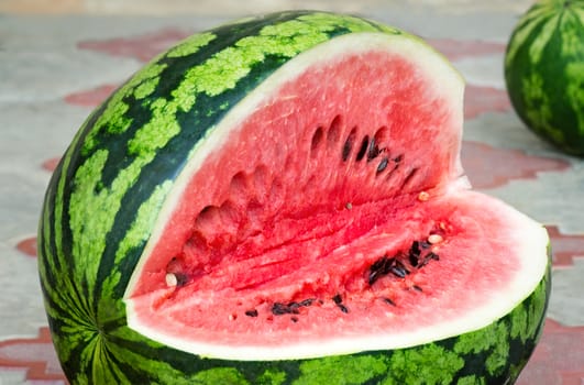 On the surface of the table on a plate of sliced watermelon with dark seeds inside. Presents closeup.