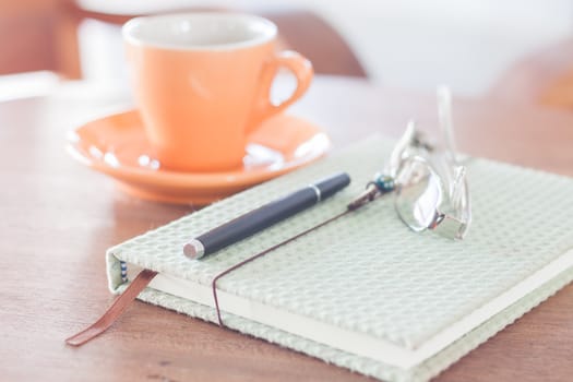 Notebook, pen and eyeglasses with orange coffee cup, stock photo