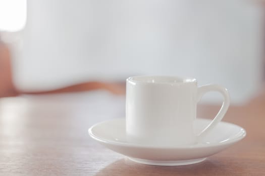 Mini white coffee cup on wooden table, stock photo