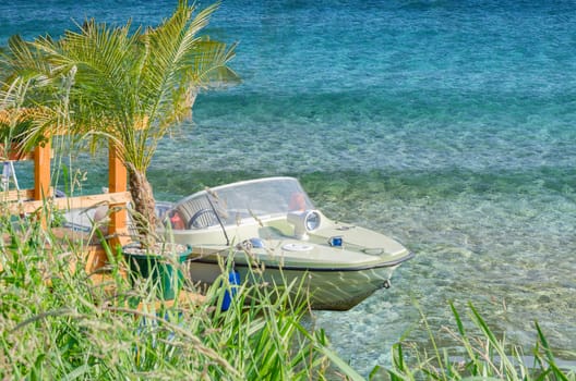 Small Engine, Sport boat in blue water moored at Steeg with palm trees.