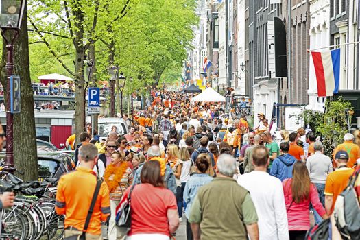 AMSTERDAM - APRIL 26: Amsterdam canals full of boats and people in orange during the celebration of kings day on April 26, 2014 in Amsterdam, The Netherlands
