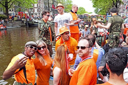 AMSTERDAM - APRIL 26: Amsterdam canals full of boats and people in orange during the celebration of kings day on April 26, 2014 in Amsterdam, The Netherlands