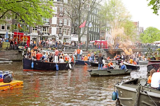 AMSTERDAM - APRIL 26: Amsterdam canals full of boats and people in orange during the celebration of kings day on April 26, 2014 in Amsterdam, The Netherlands