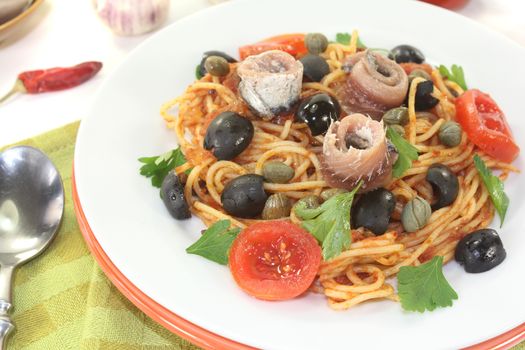 Spaghetti alla puttanesca with anchovy on light background