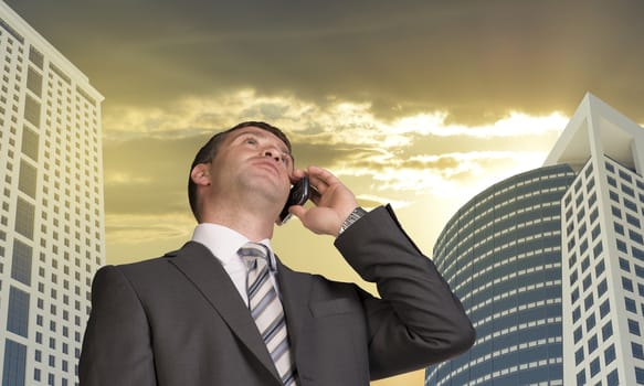 Businessman talking on the phone. Skyscrapers and clouds in background