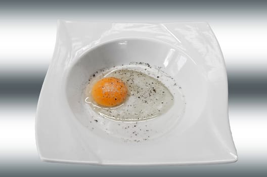 Yolk of a raw whipped egg in a white plate.
