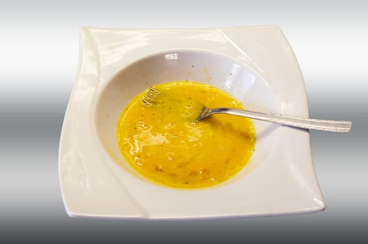 Egg yolk stirred into a white plate against an off-white background.
