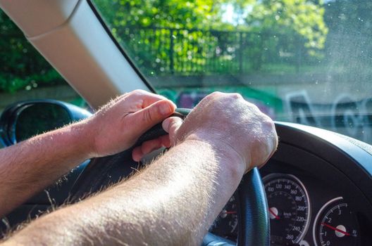 Driving a car hands on the wheel overlooking the speedometer.
