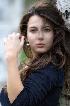 portrait of a beautiful brunette standing in birch forest