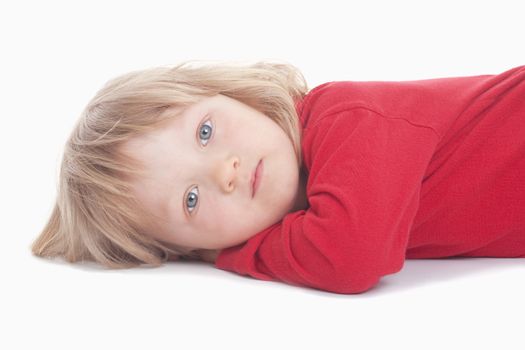 boy with long blond hair lying down, looking at camera - isolated on white