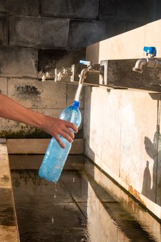 Hand filling water bottle on a public fountain
