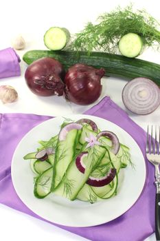 Cucumber salad with onions, garlic flower and dill on light background