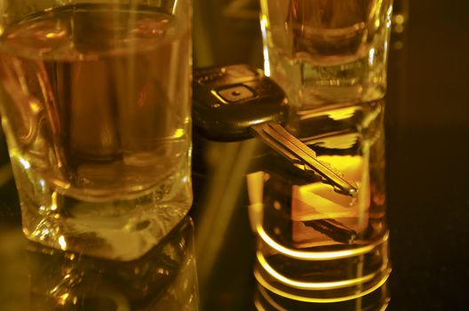 two whiskey shots on the bar shelf with car key between them; focus on key