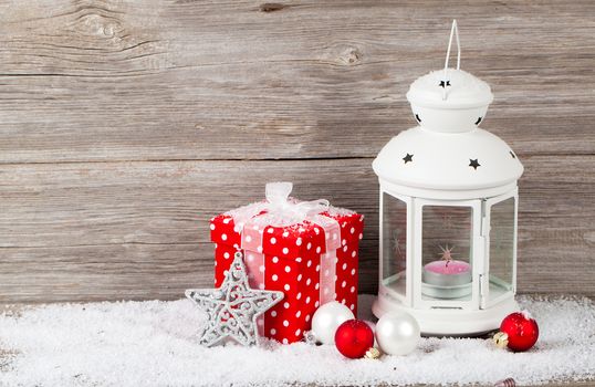 Christmas decoration with candle in lantern and fir tree branches on wooden background