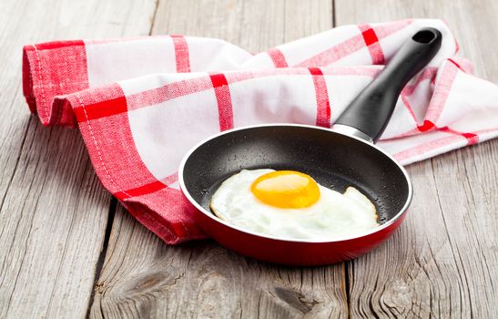 Fried egg in a frying pan, on an old wooden table