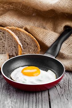 Fried egg in a frying pan, on an old wooden table