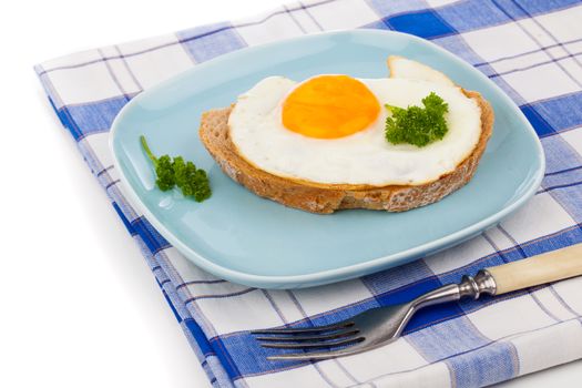 fried egg in blue plate with fork, over white background