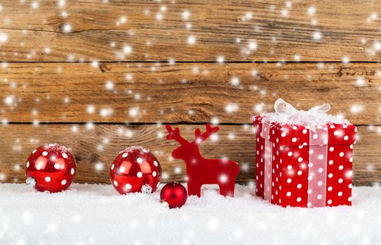 red gift for christmas on a wooden background with snow