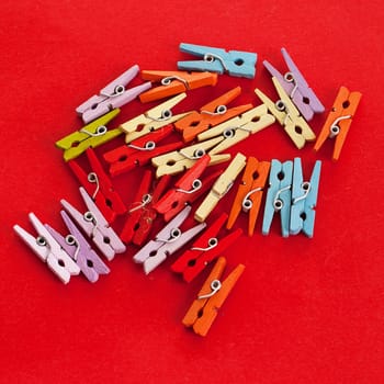 Closeup image of little colorful office clothespins on a red background