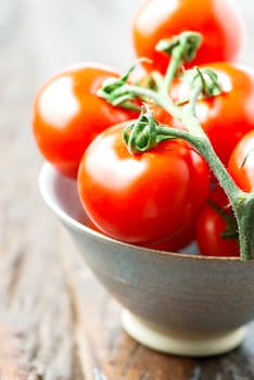 Tomatoes in a bowl on old wooden table close up